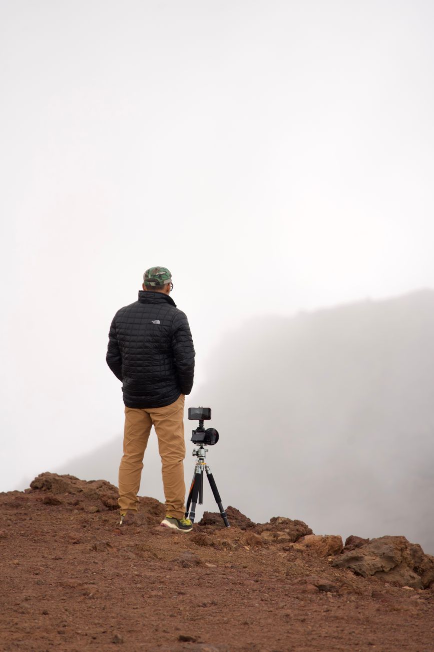 Travel photographer observing mountain mist from high pass
