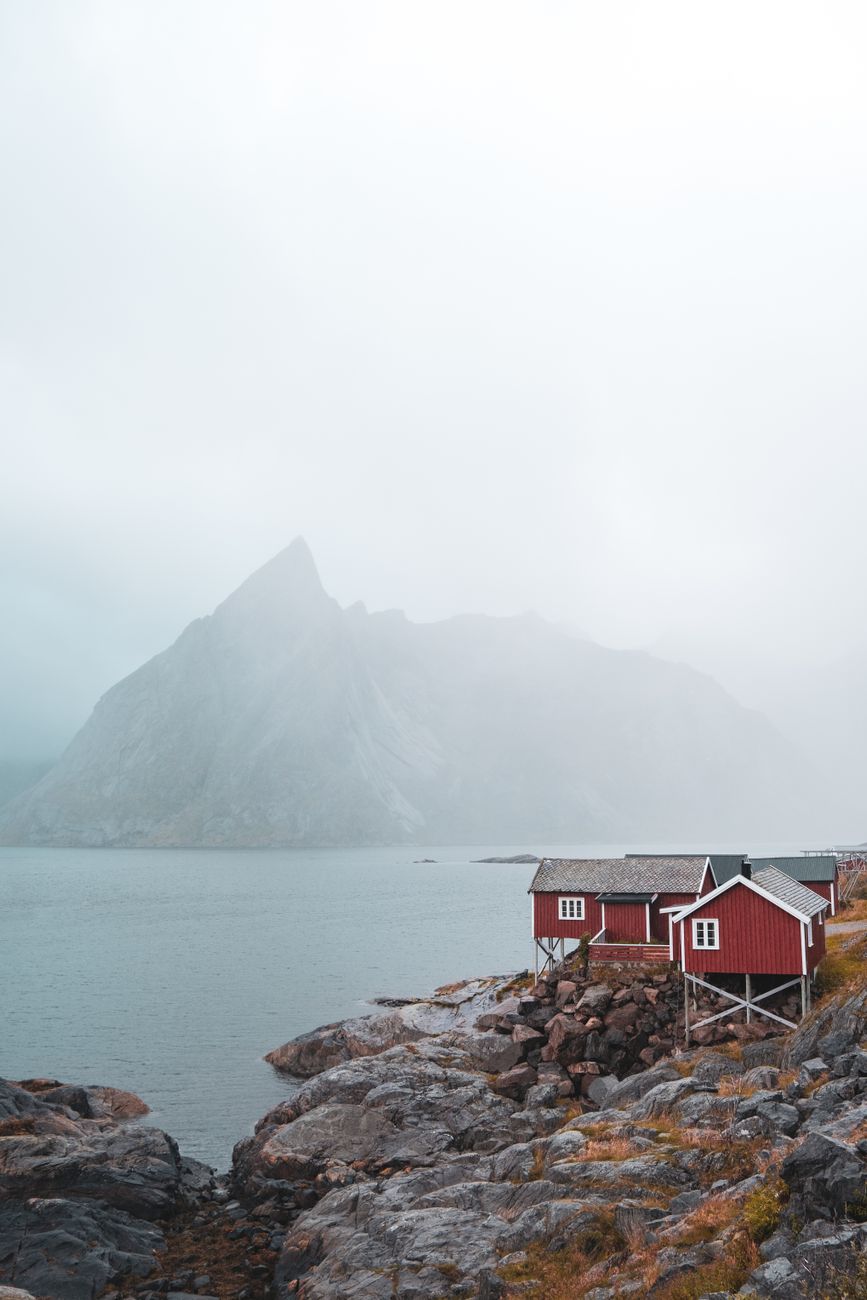 Foggy morning view of red timber cabins along the arctic coastline