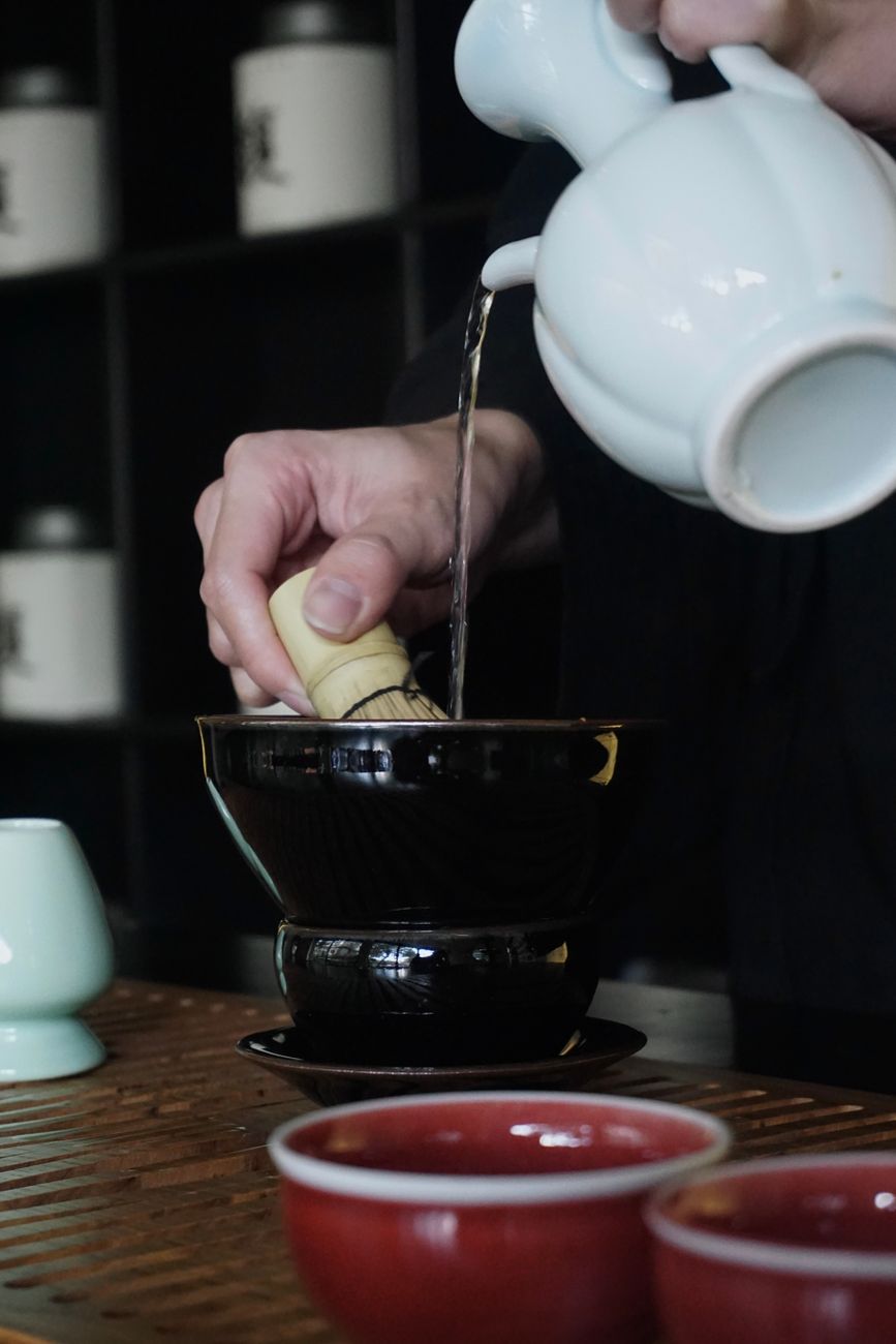 Close-up of ceramic master serving green tea on cedar tray